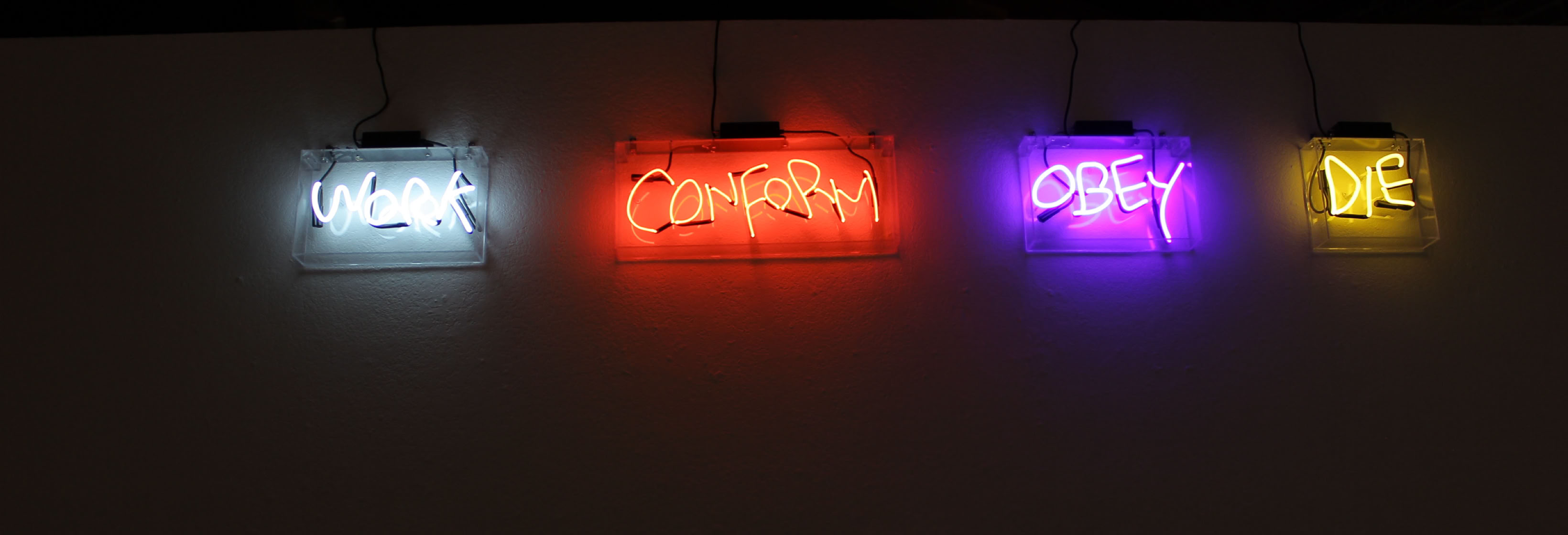 Neon signs on a wall displaying the words "Work" in white, "Conquer" in red, "Obey" in purple, and "Me" in yellow. Colors reference the four horsemen of the apocalypse